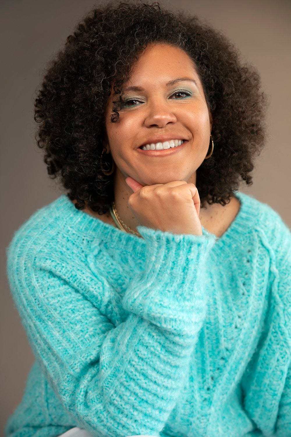 Headshot of today's guest, Jessica Wilson, wearing a light blue, knitted jumper, against a brown backdrop