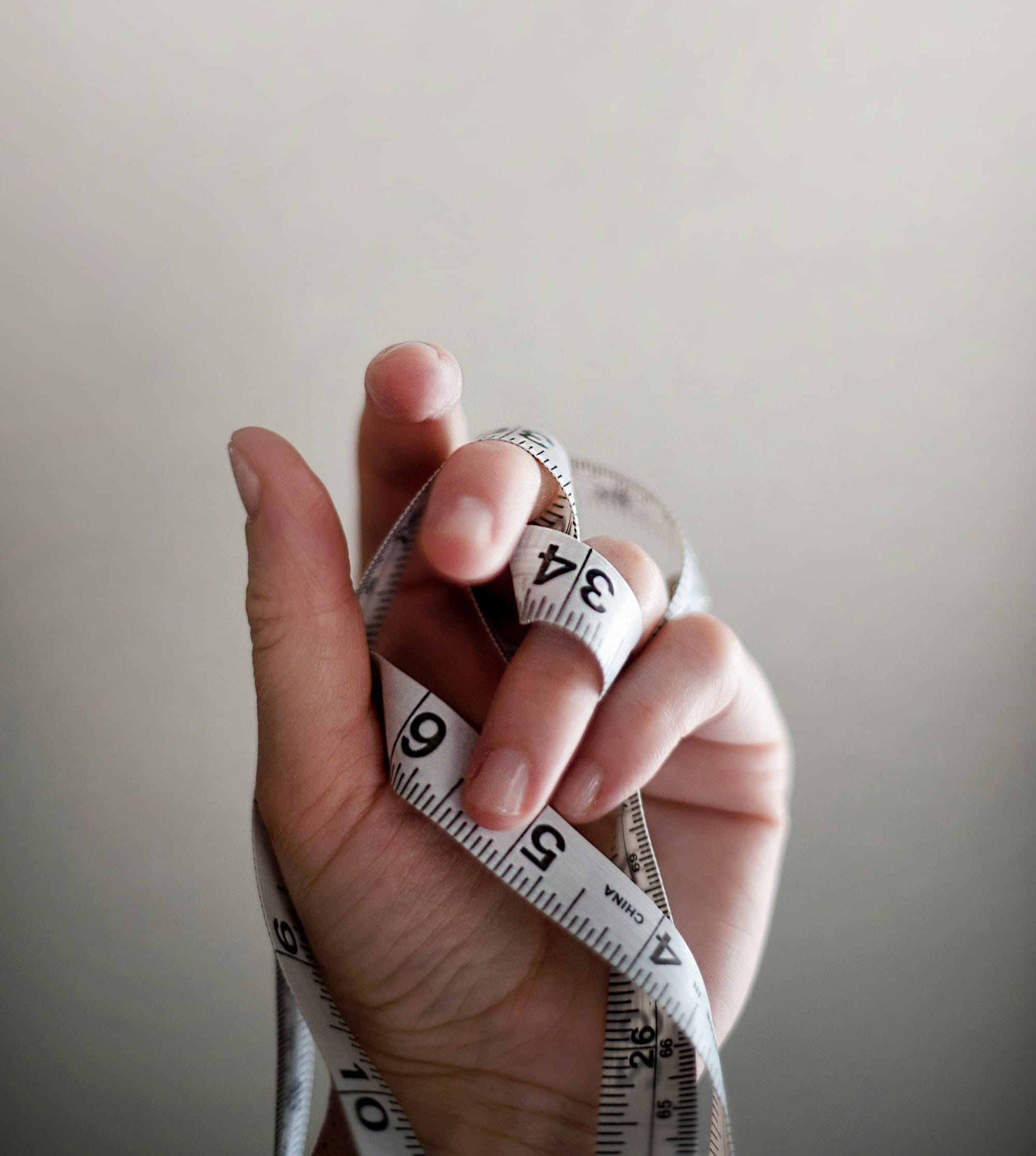 person's left hand wrapped by tape measure